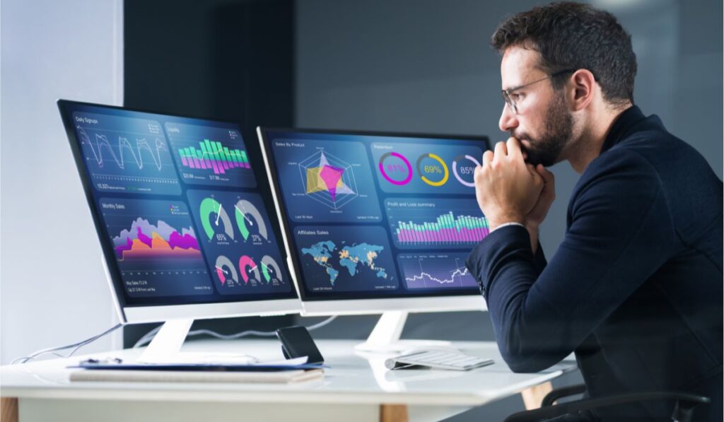 imagem de um rapaz olhando para telas de computadores e gráficos com dados em alusão ao big data analytics