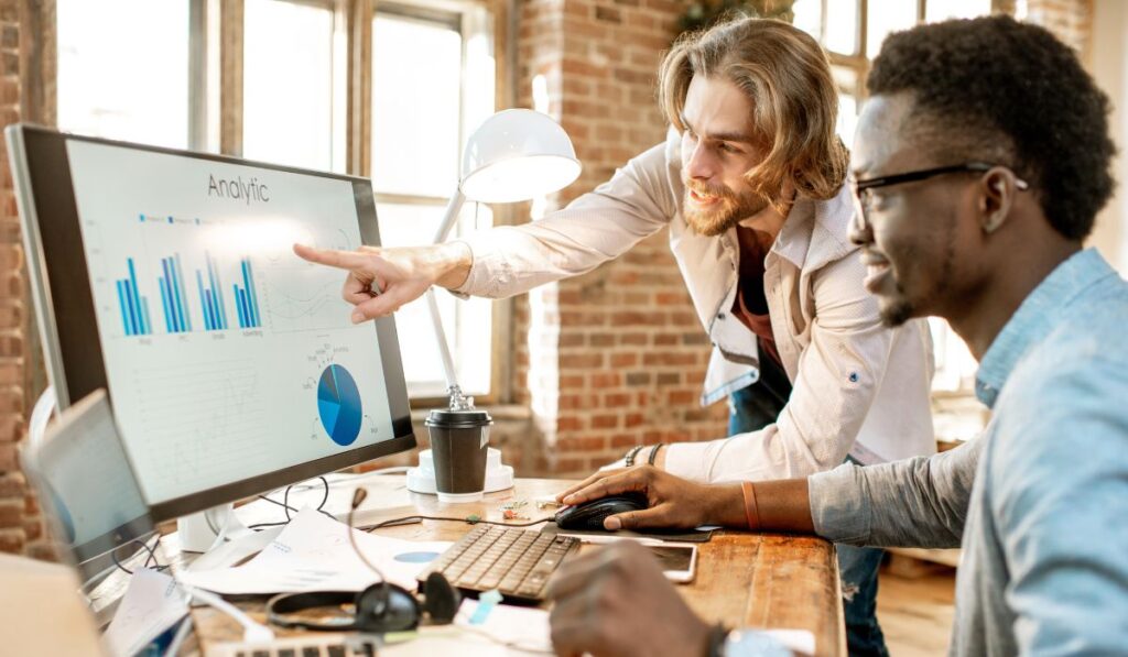 imagem de dois rapazes olhando para um computador com dados em referência ao big data analytics