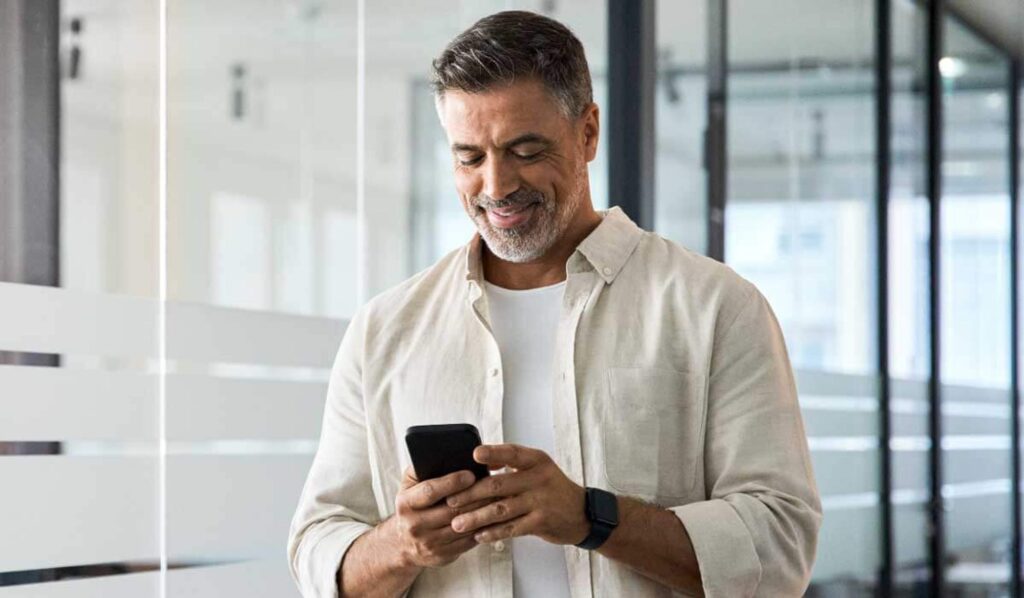 imagem de um homem grisalho olhando o celular e sorrindo