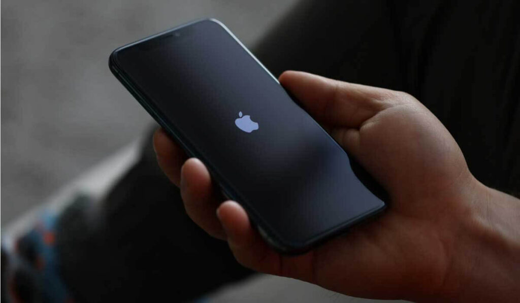 imagem uma mão segurando um celular preto da Apple