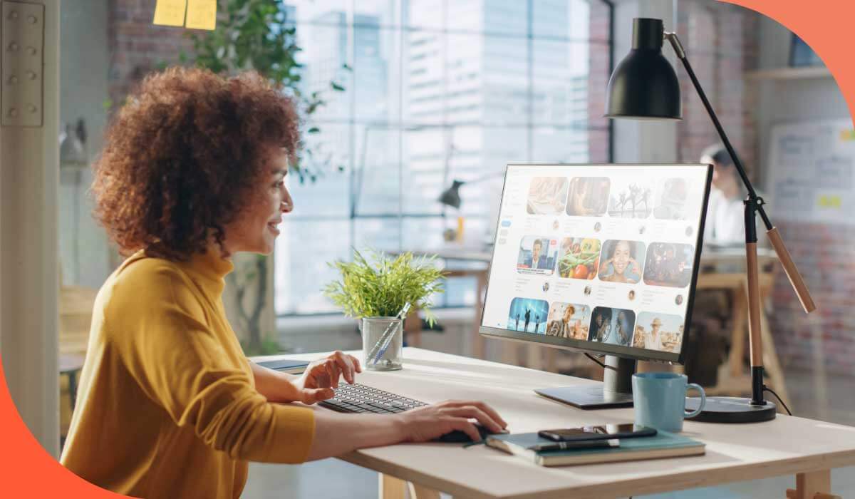 imagem de uma mulher vestindo blusa amarela sorrindo e olhando para uma tela de computador