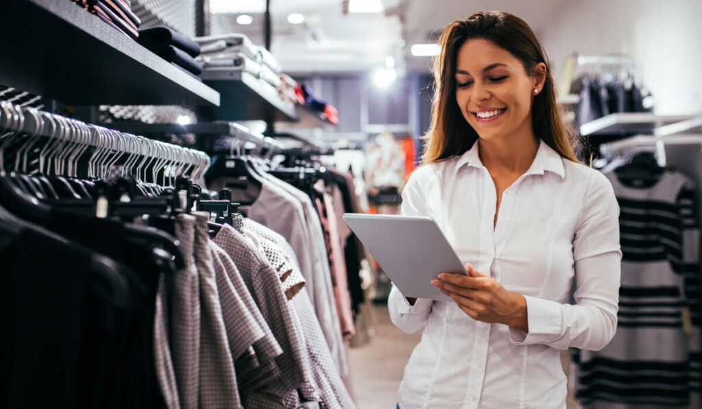 imagem de uma moça olhando um tablet em uma loja como se tivesse fazendo vendas digitais