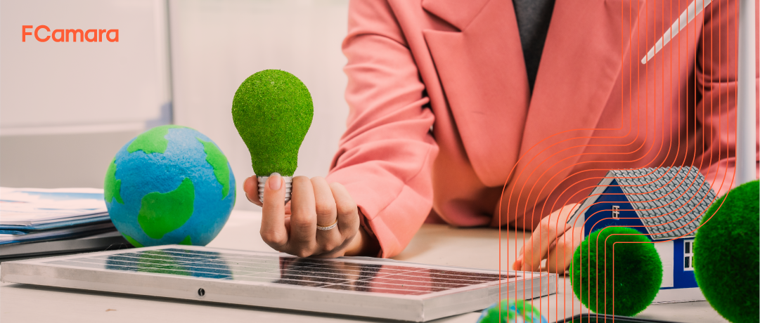 Executiva com paletó rosa segurando uma lâmpada pintada de verde para ilustrar o tema inovação sustentável