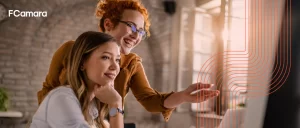 Dupla de profissionais analisando sorridentes no computador métricas de e commerce